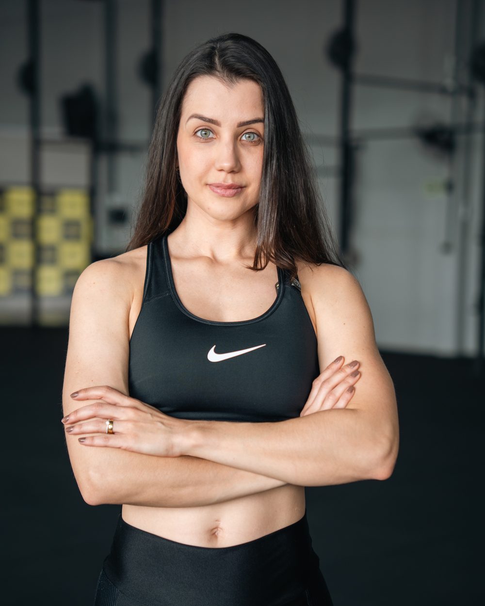 Ana Bolognini de braços cruzados na academia, olhando para a câmera